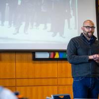 man presenting in front of projector with black and white photo behind them